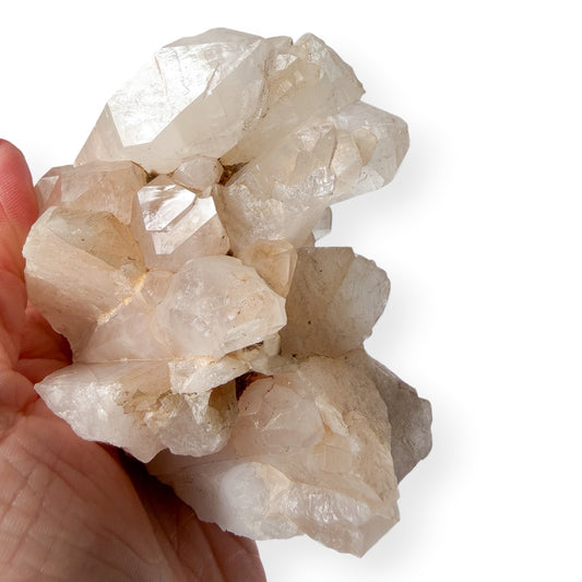 Hand holding a cluster of crystal rocks against a white background