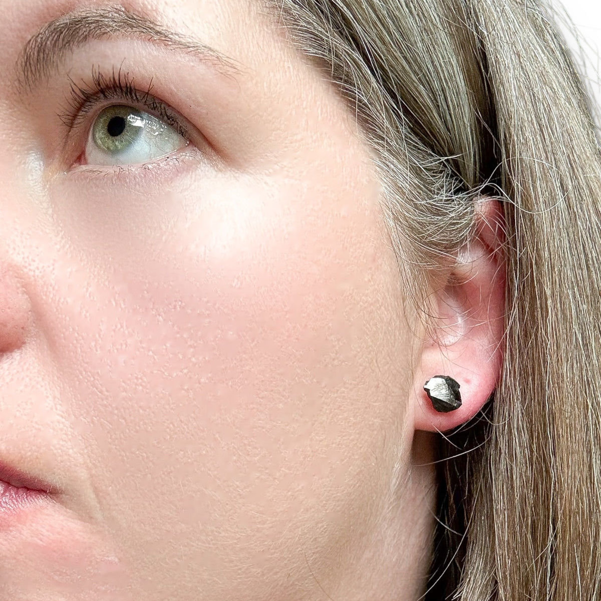 A woman wearing a noble shungite stud in her left ear.