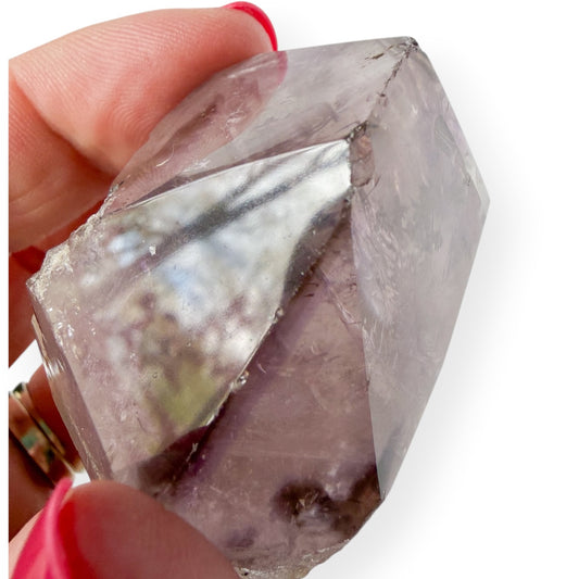 Small Amethyst Close Up Chipped Point in hand with a white background
