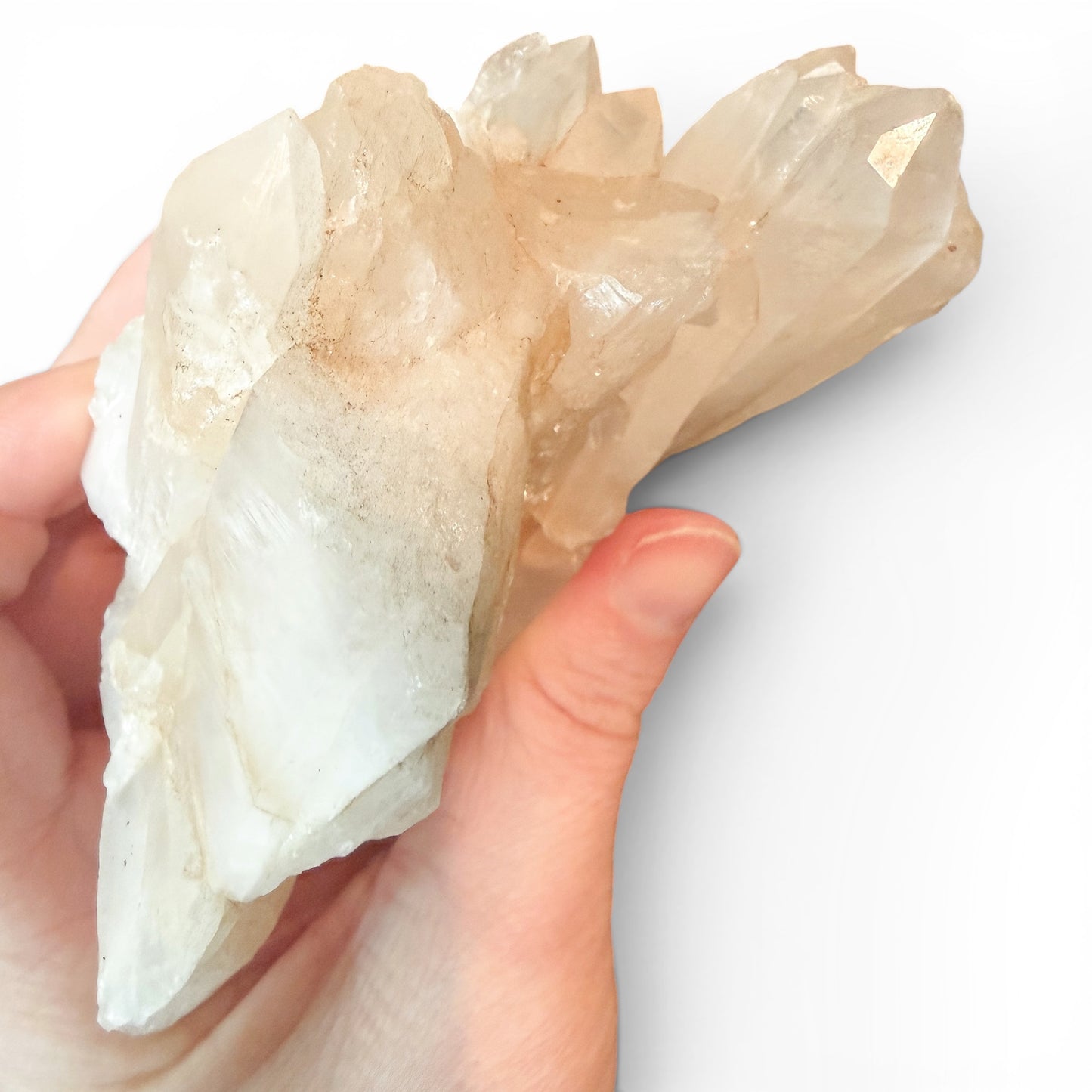 Hand holding a large crystal cluster against a white background