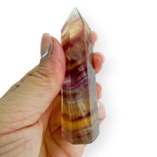 Yellow and purple striped fluorite in hand to show details in size.