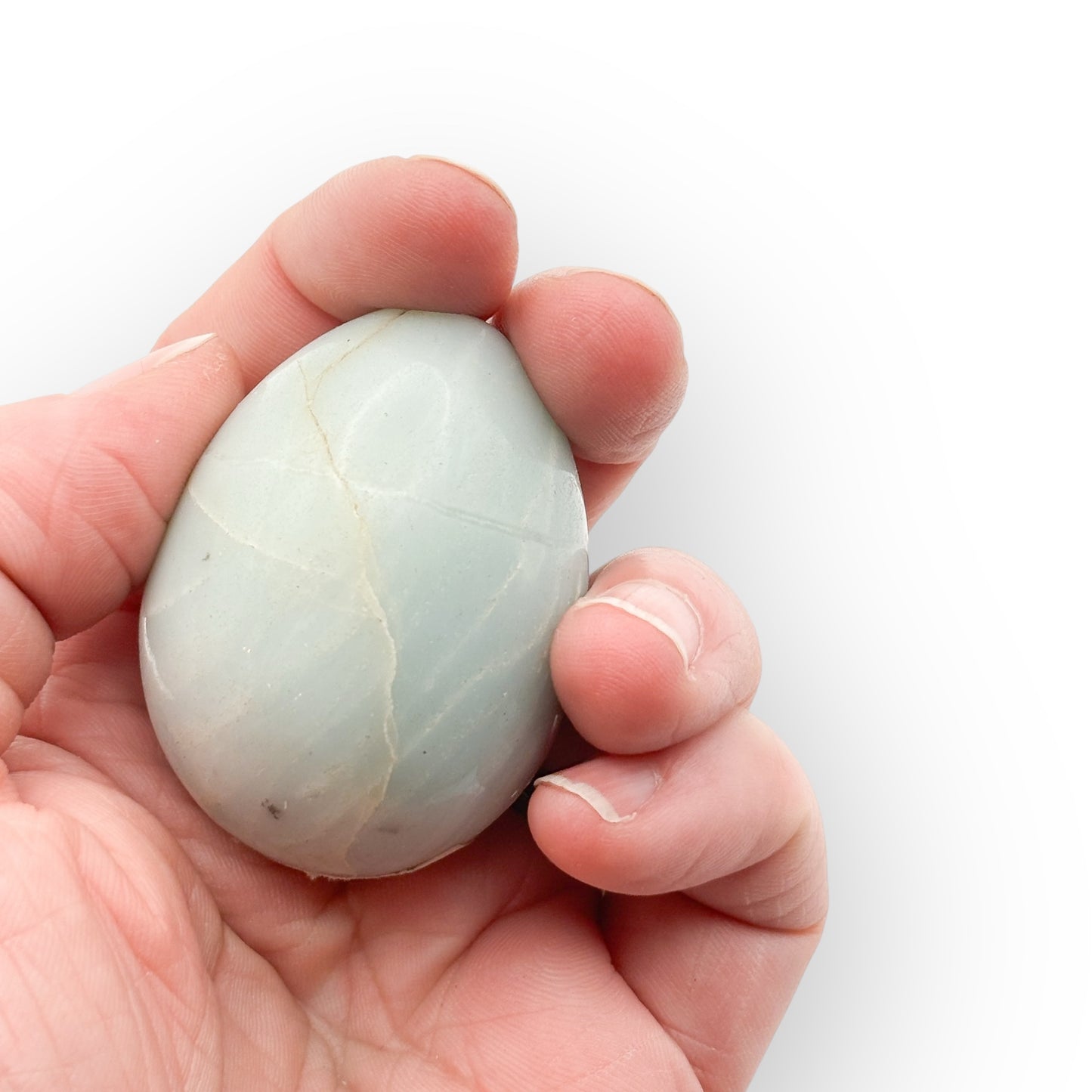 Small Amazonite egg held in hand showing soft blue-green color and natural veining