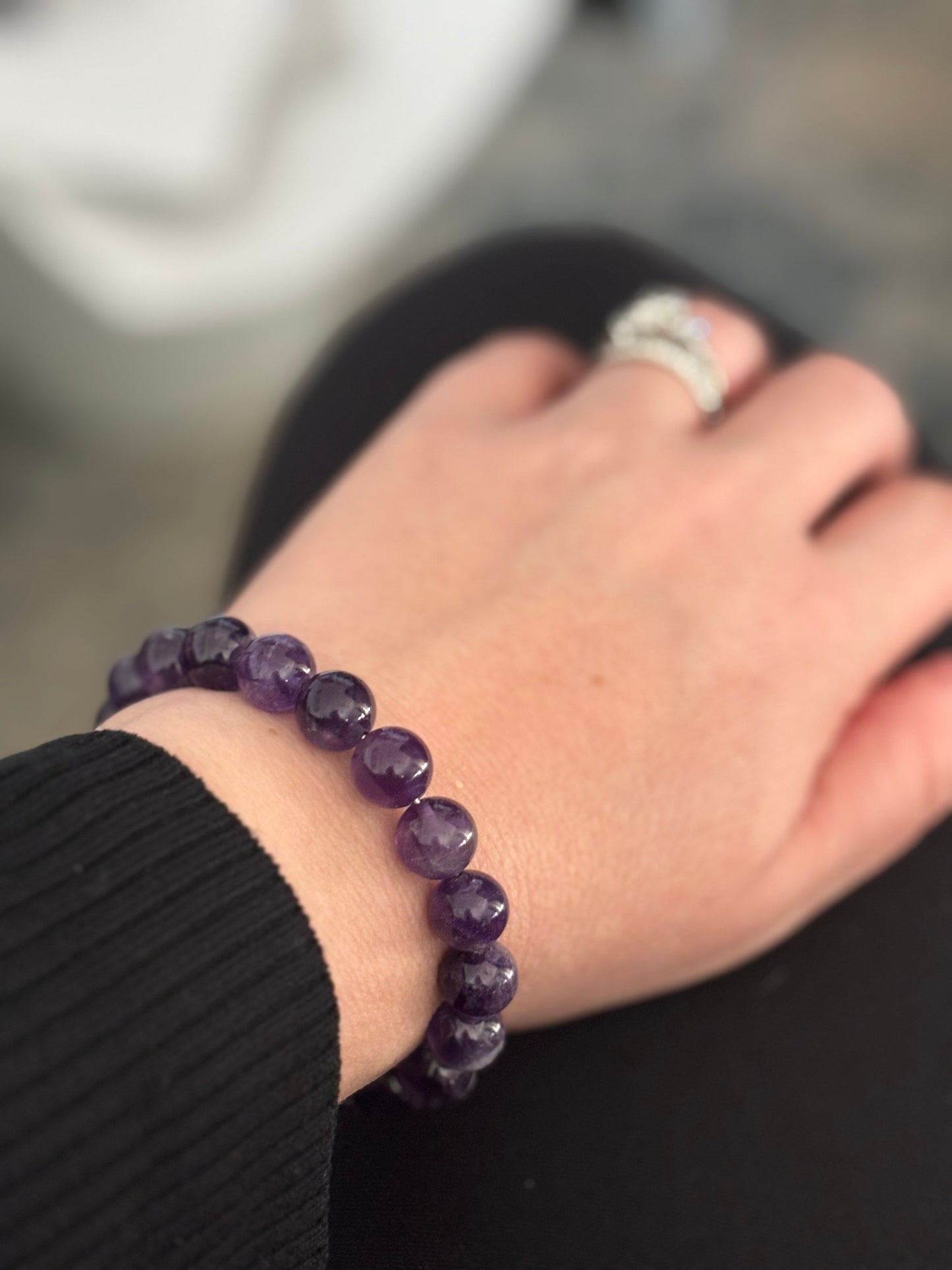Amethyst beaded bracelet on a woman's wrist, complementing a casual outfit.