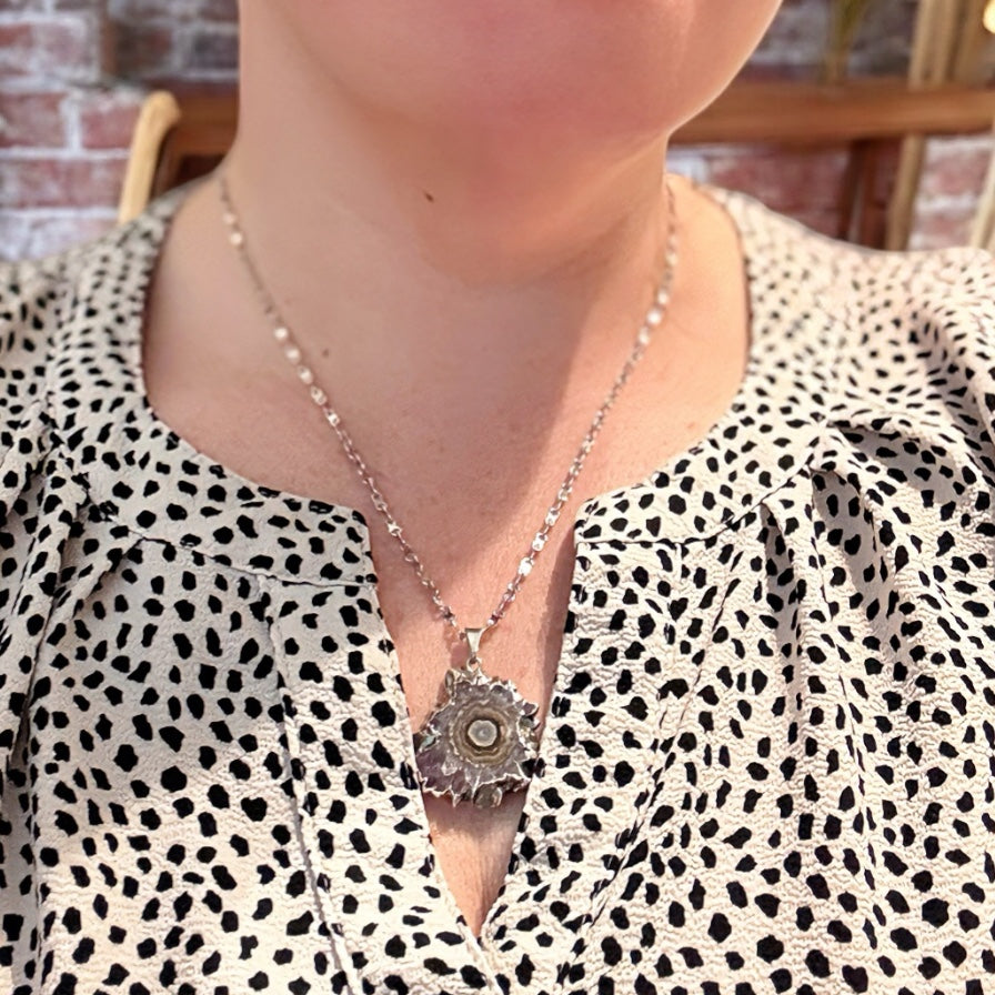 Full view of amethyst slice pendant necklace with silver setting and textured crystal core.