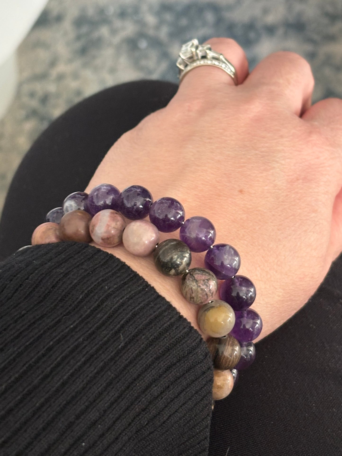 Amethyst crystal bracelet stacked with other gemstone bracelets for a layered look.