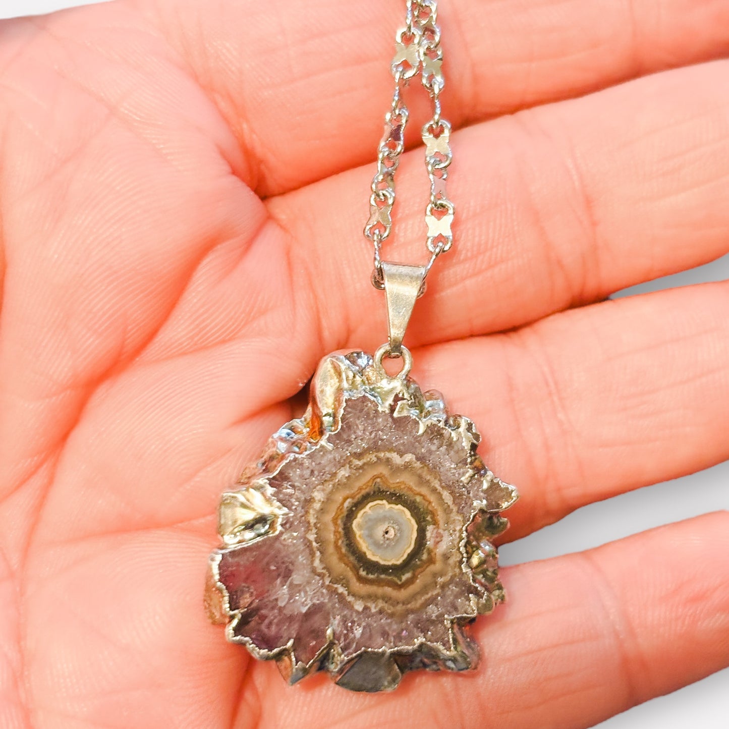 Close-up of natural amethyst stalactite pendant showing lavender crystals and green center.