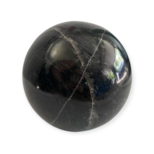 Polished black marble sphere showing smooth finish and white streaks