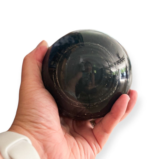 Hand holding a Black Obsidian sphere for grounding energy