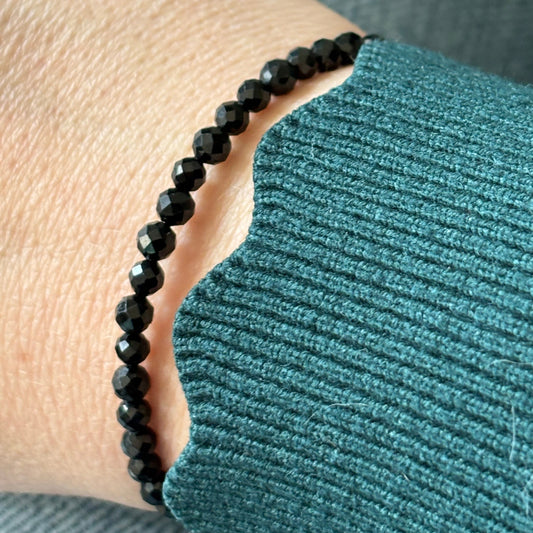 Black Tourmaline wrap bracelet worn on wrist, highlighting its flexible stainless steel band and sleek design.