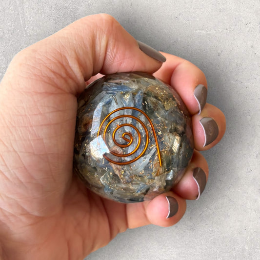 Blue Kyanite Orgone Sphere with copper spiral held in hand for scale