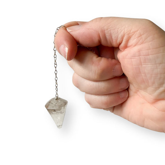 Clear quartz dowsing pendulum held in hand as a spiritual tool
