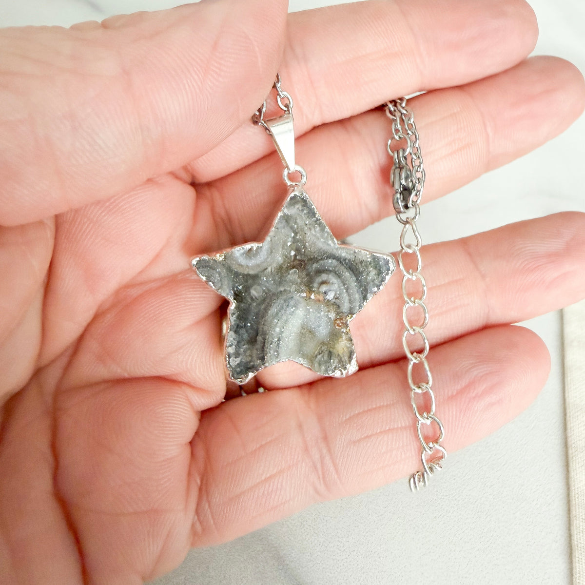 Close up detail ofsStar shaped drusy crystal silver plated pendant necklace on stainless steel chain