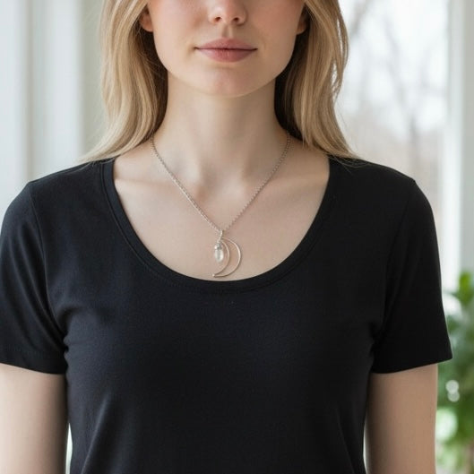 Modeled view of a silver plated crescent moon necklace with clear quartz crystal on a stainless steel chain, shown in an AI generated lifestyle image.