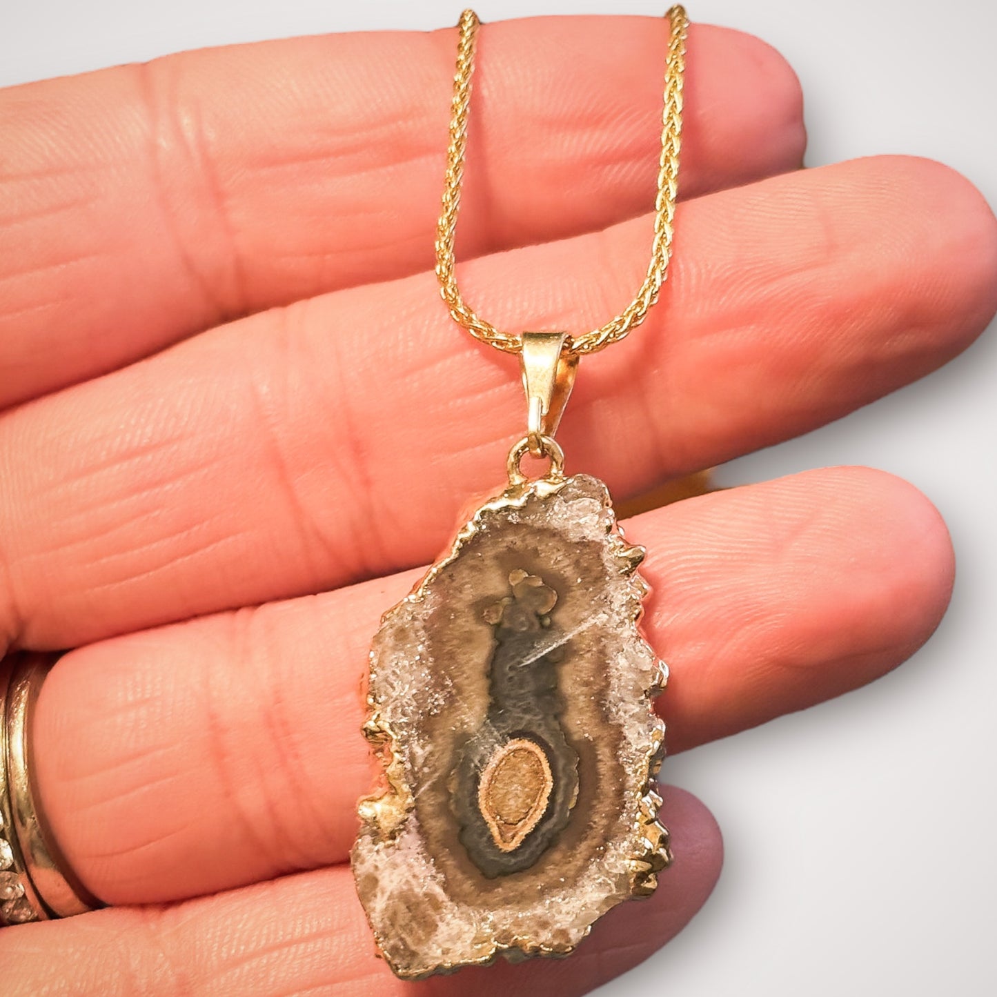Gold amethyst stalactite necklace resting in palm of hand to show scale