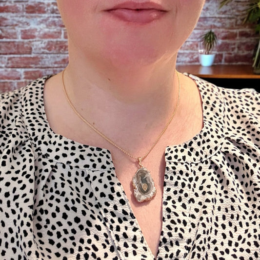 Woman wearing gold amethyst stalactite necklace with soft purple and green tones