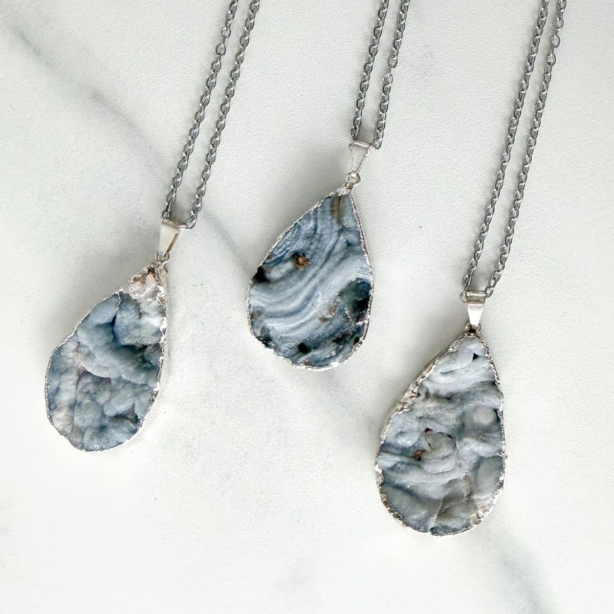 Gray teardrop drusy crystal pendant with natural sparkle in a sterling silver plated setting.