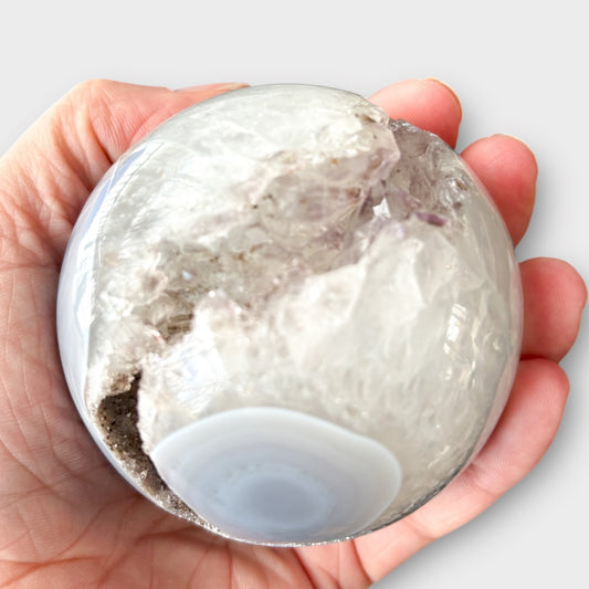 Hand holding Gray and White Agate Druzy Sphere with exposed druzy pocket.