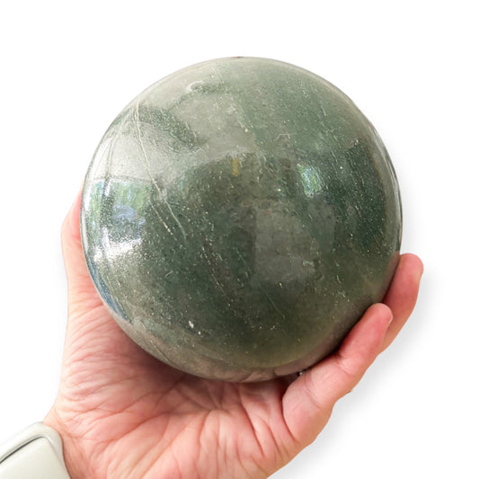Hand holding a Green Aventurine sphere for emotional healing