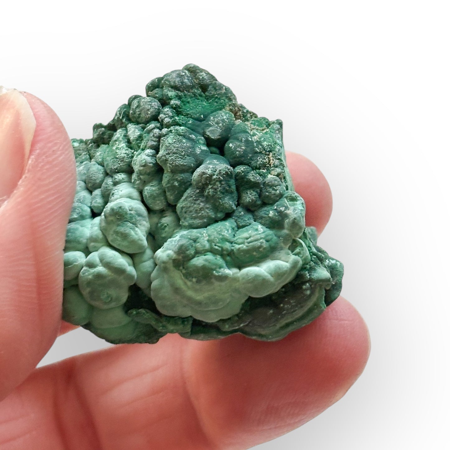 Rough Green Malachite stone held in hand to show size and texture