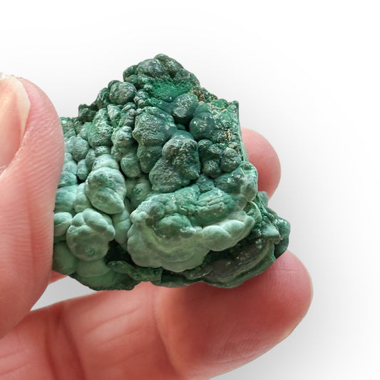 Rough Green Malachite stone held in hand to show size and texture