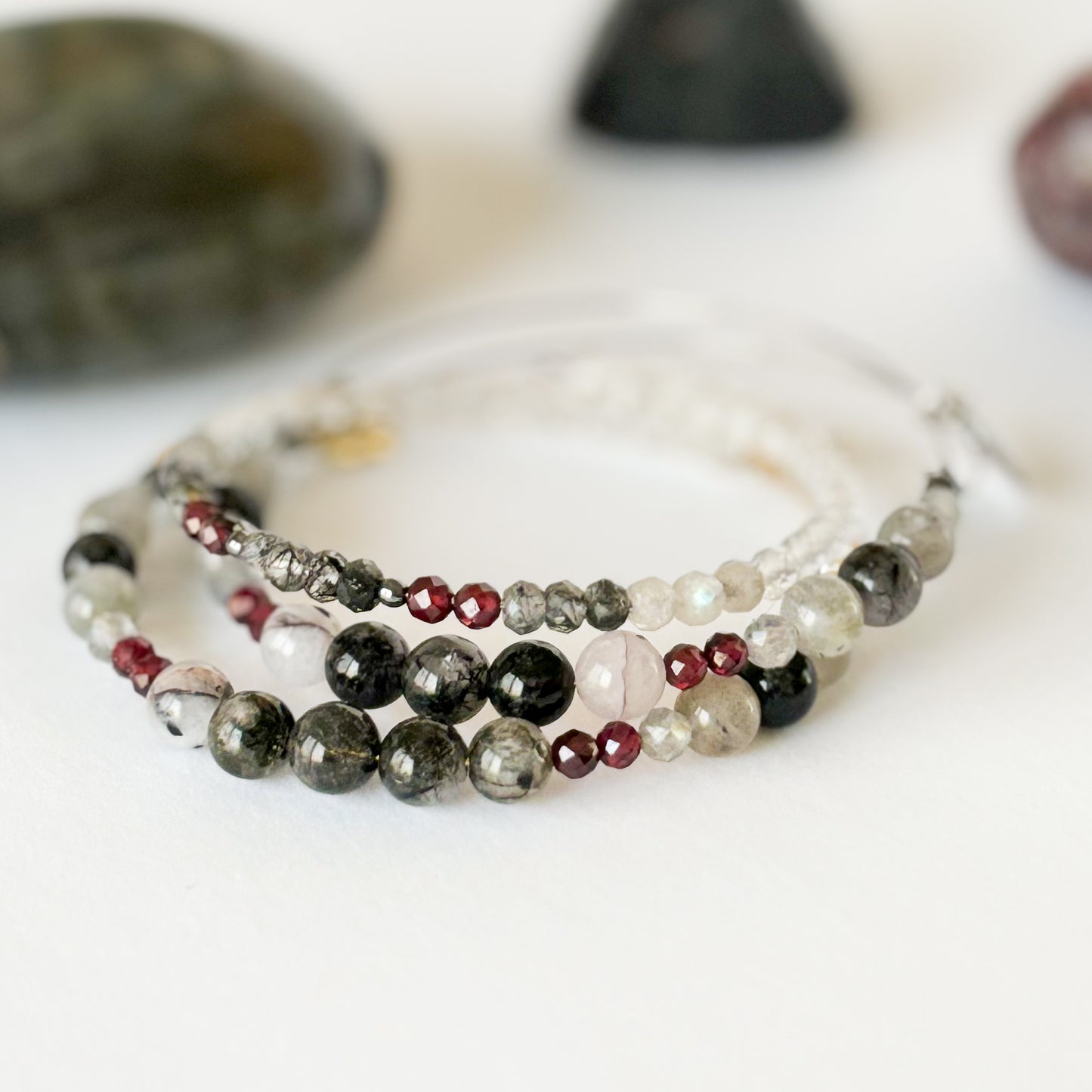 Stacked flexible stainless steel crystal bangle bracelets with dark and light gemstones