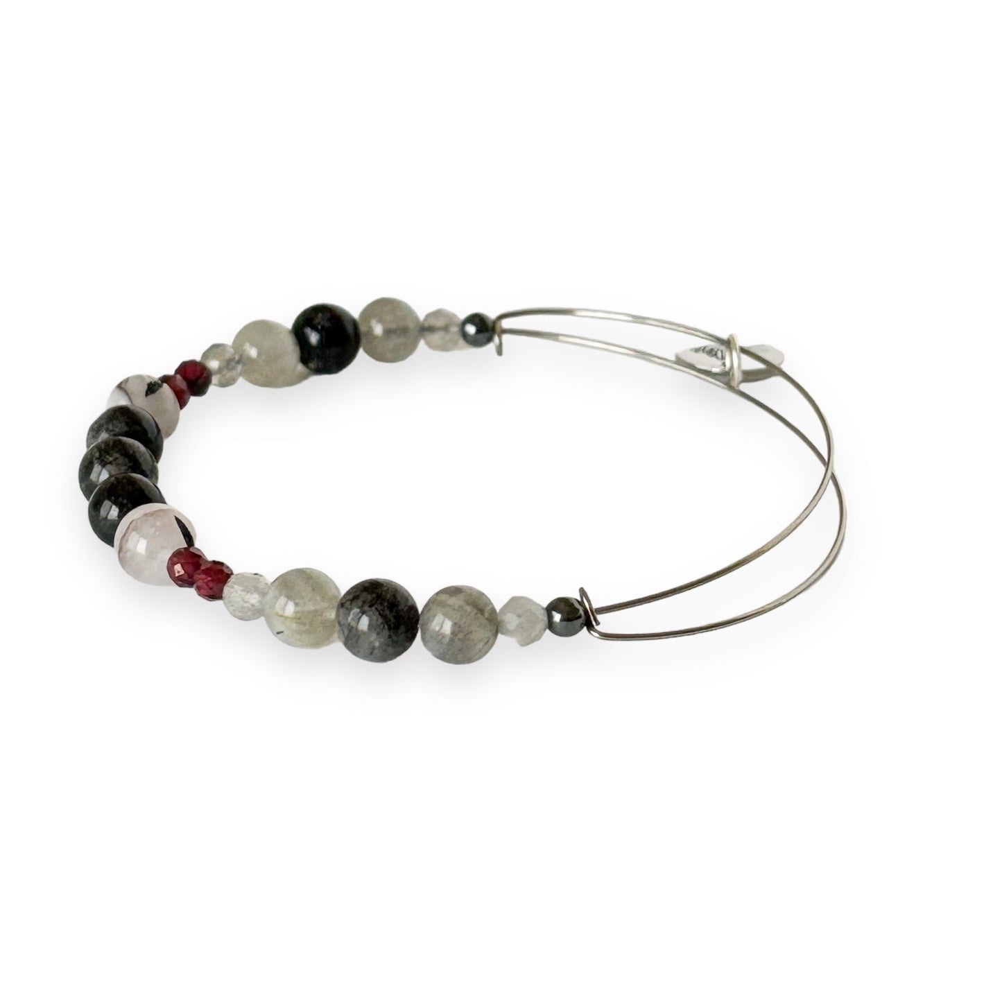 Close-up of crystal bangle bracelet with red garnet, tourmaline in quartz, and labradorite