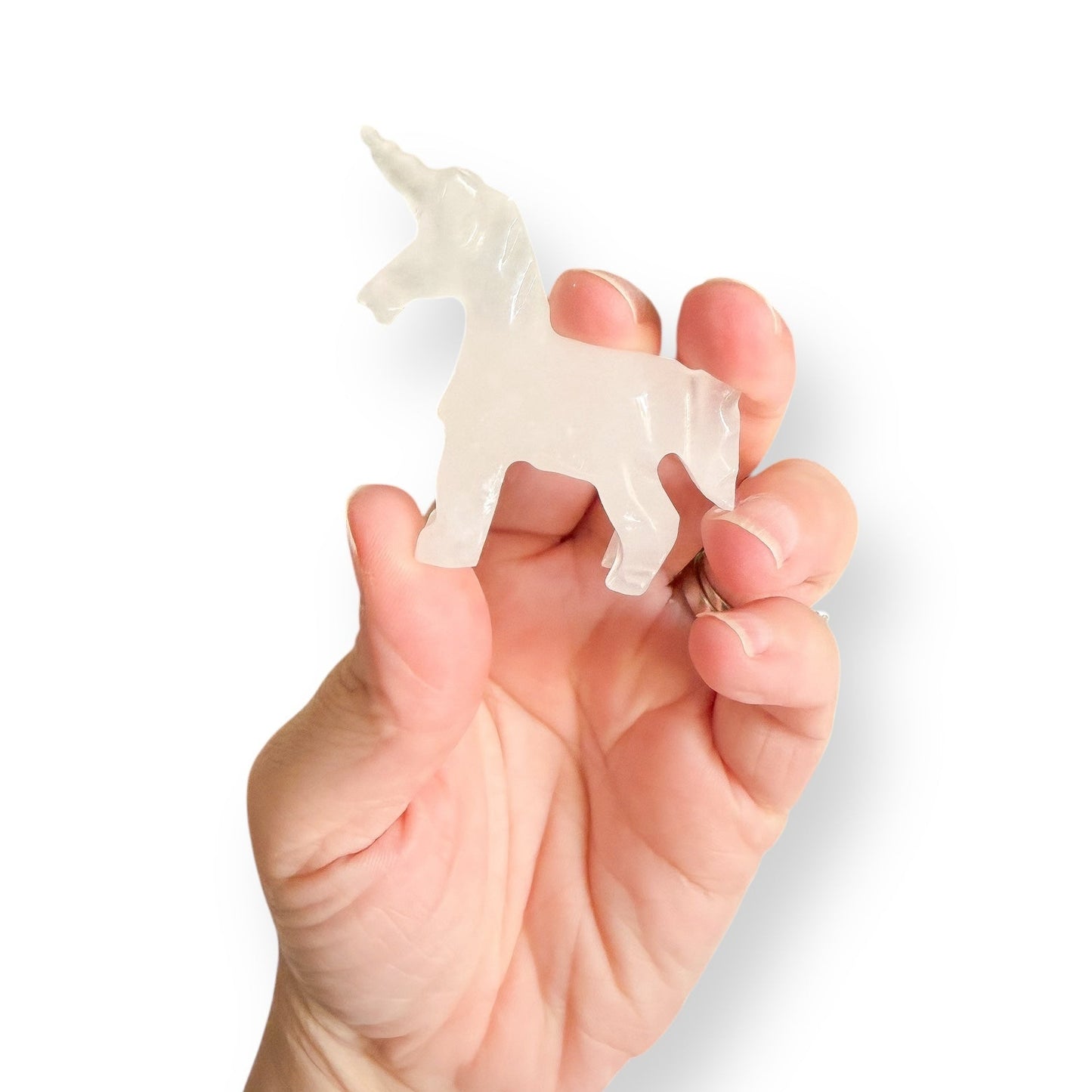 Hand holding large calcite unicorn figurine made from white calcite.