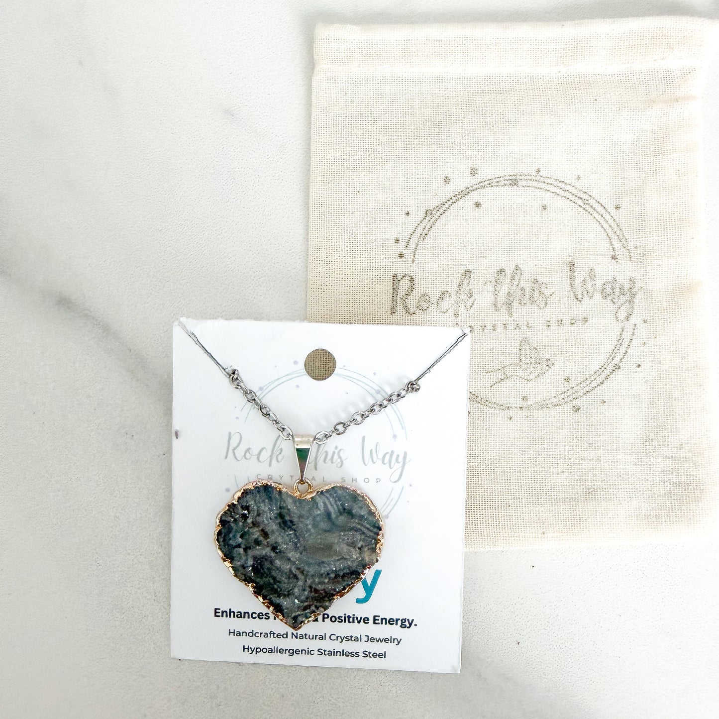 Silver plated heart drusy pendant necklace displayed on Rock This Way Crystal Shop packaging with included polishing cloth.