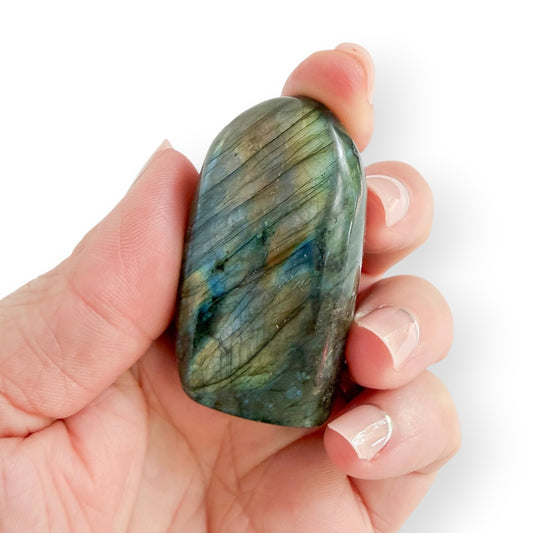 Hand holding a Labradorite free form showing natural green, gray, and blue coloration.