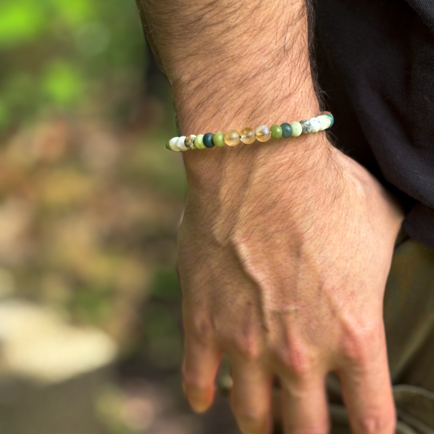 Success crystal bracelet for men worn on wrist with green, orange, and gold beads