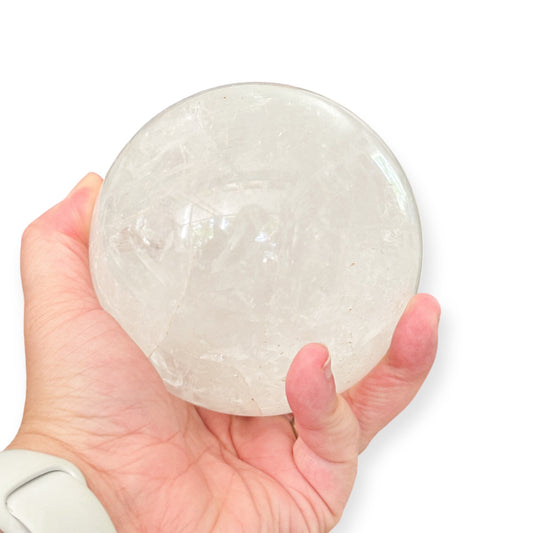 Hand holding a palm-sized Milky Quartz crystal sphere