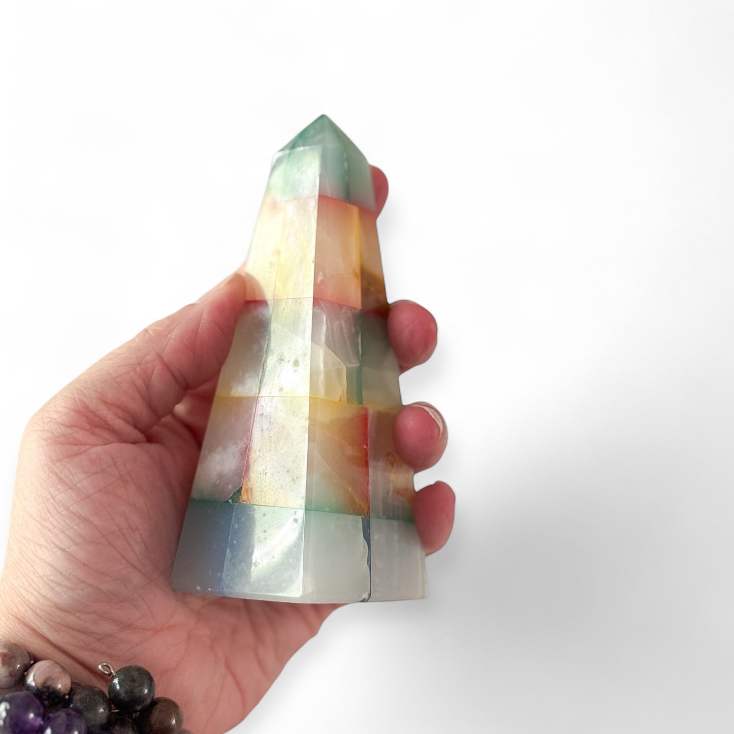 Hand holding patchwork onyx obelisk for size reference