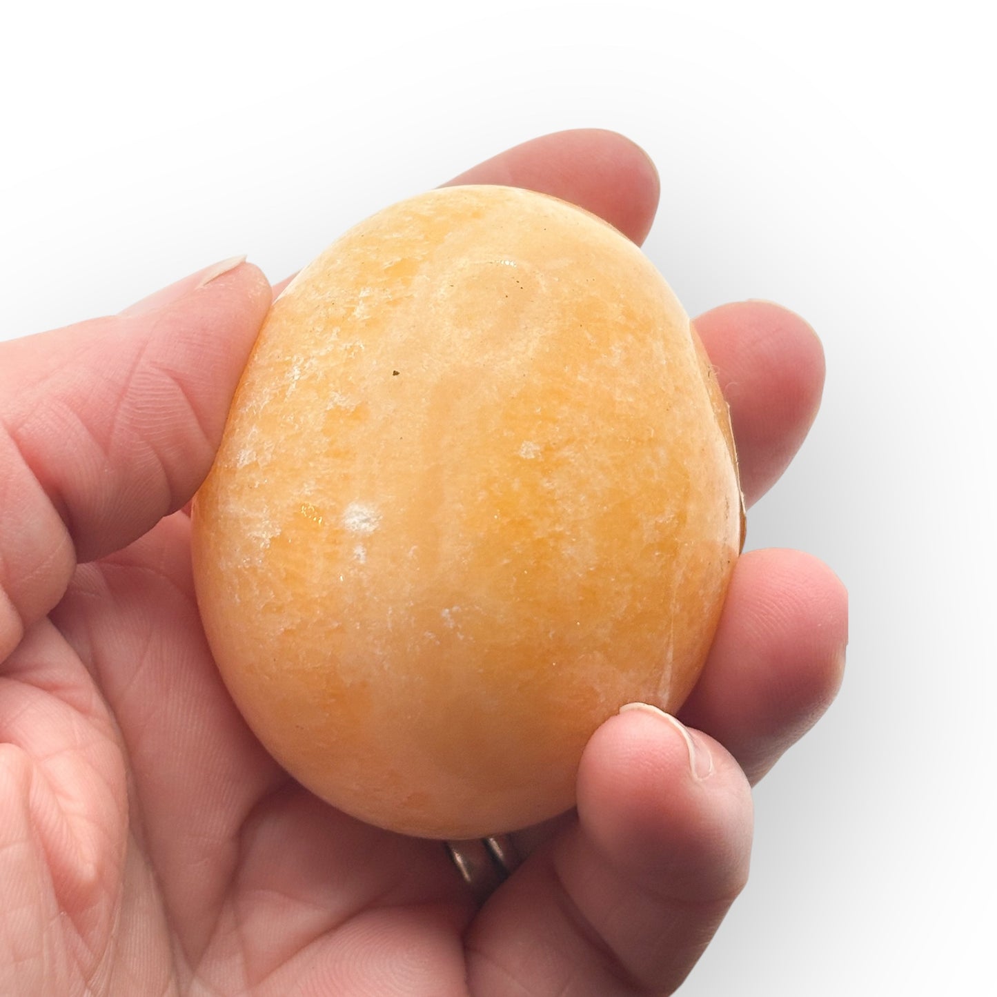 Palm-sized Orange Calcite egg held in hand with bright, sunny color and smooth finish