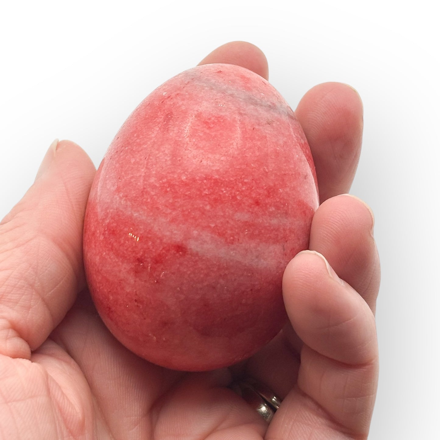 Palm-sized Pink Agate egg held in hand showing deep pink hues and natural banding
