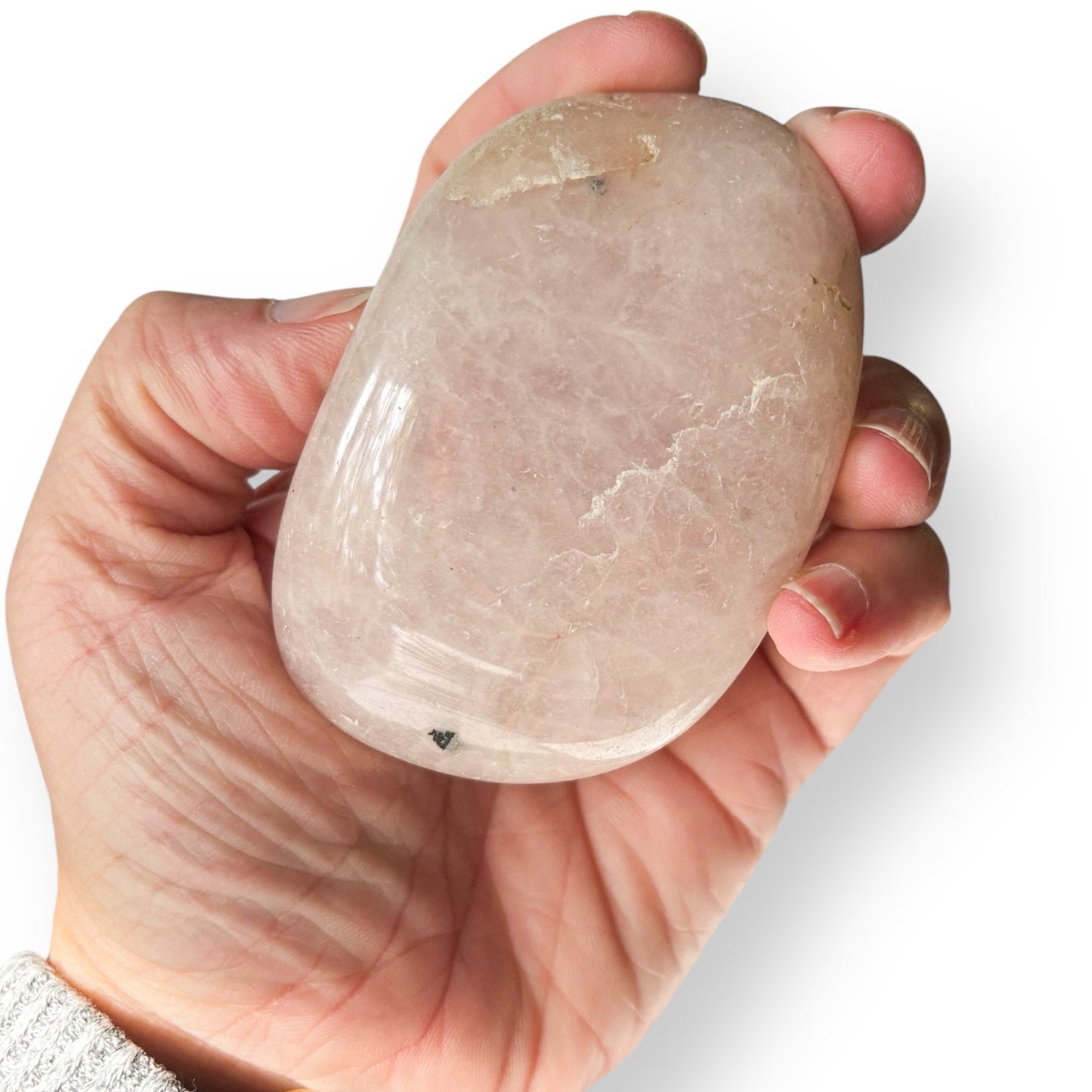 Hand holding a rose quartz crystal against a white background