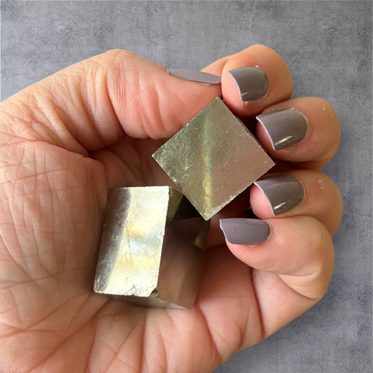 Hand holding a small Pyrite Cube – scale and shine visible