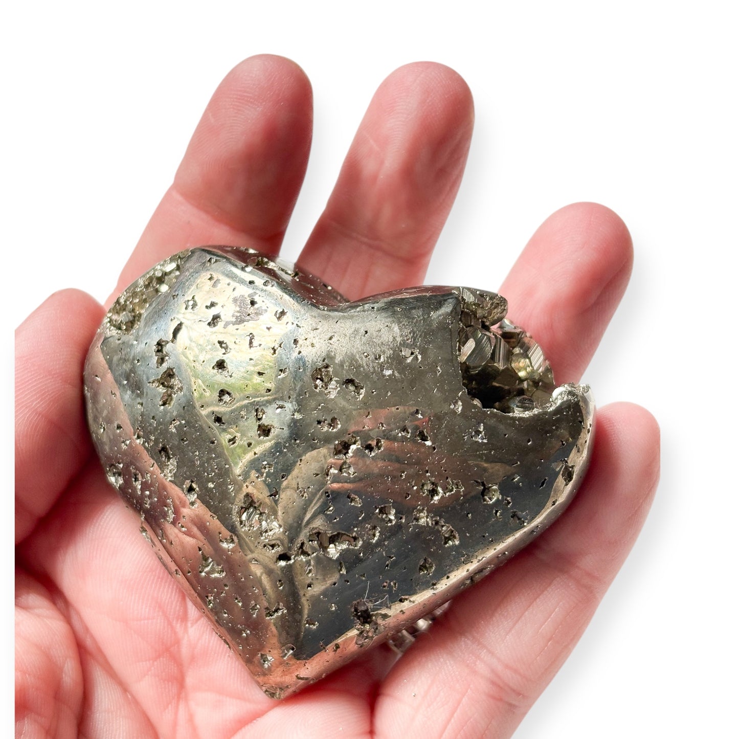 Hand holding raw Pyrite heart crystal to show scale and detail