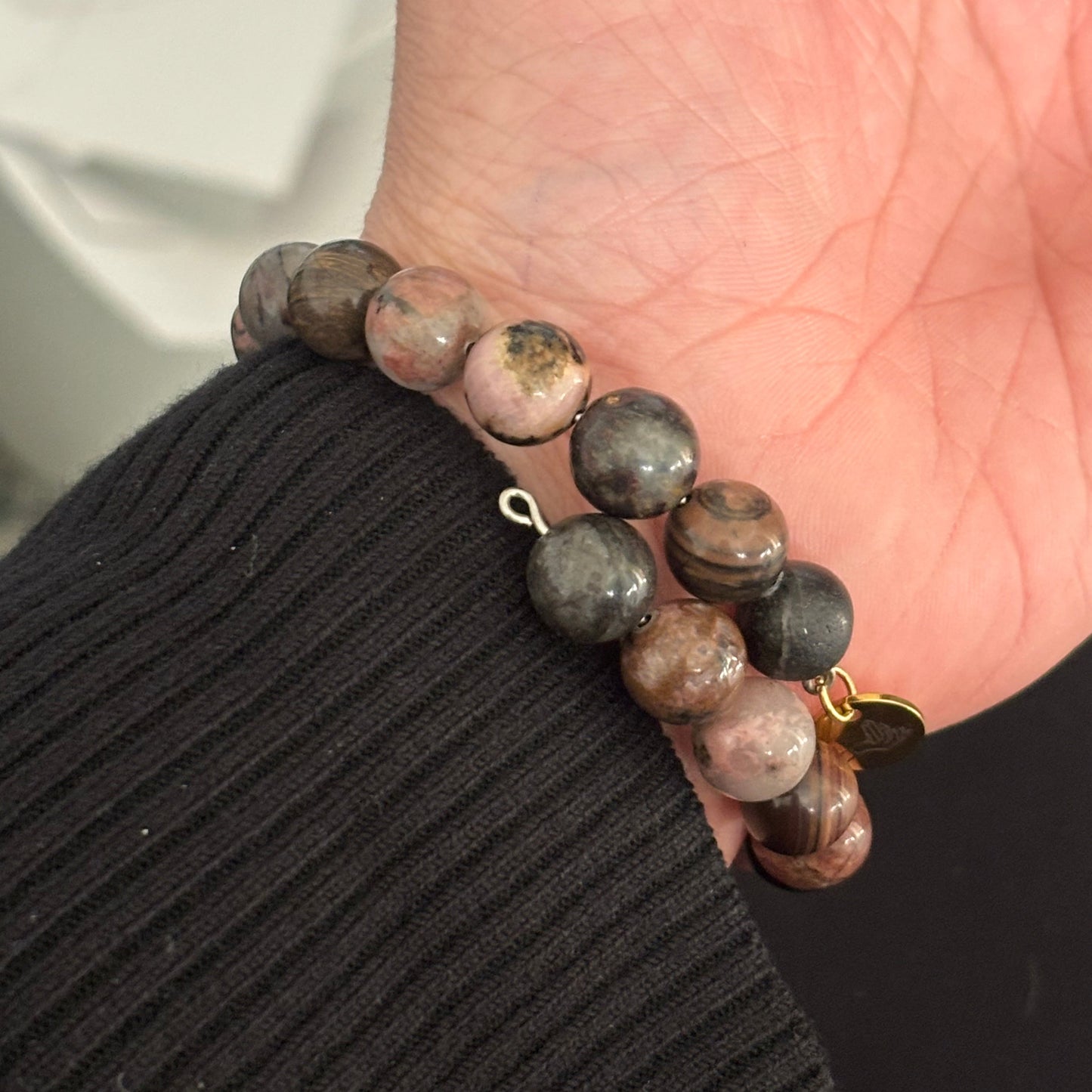 Soft pink and earthy tones of Rhodonite beads, symbolizing compassion and resilience.
