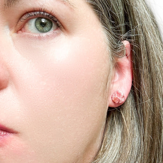 Close-up of rhodonite rough stud earring worn on ear