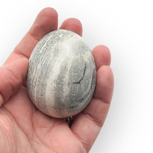 Medium Rhyolite egg held in hand showing natural earthy tones and grounding patterns