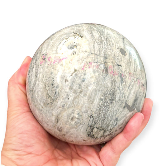 Hand holding a polished Rhyolite crystal sphere