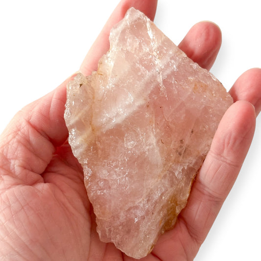 Hand holding medium rough Rose Quartz for size and texture reference