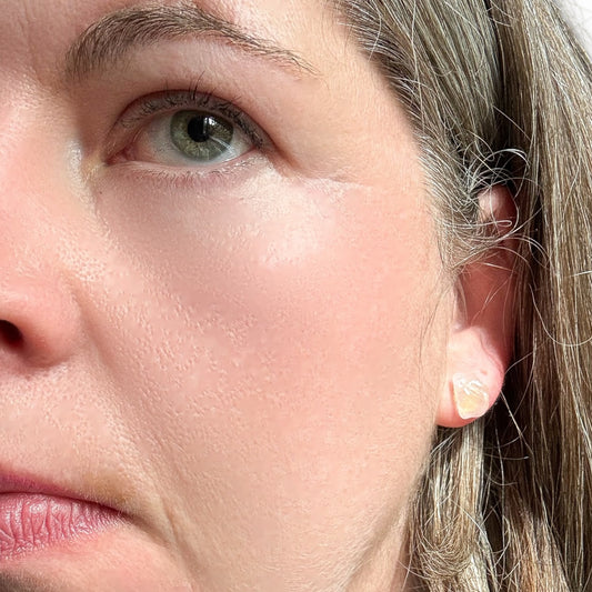 Close-up of rose quartz crystal earrings worn on ear, polished natural stone