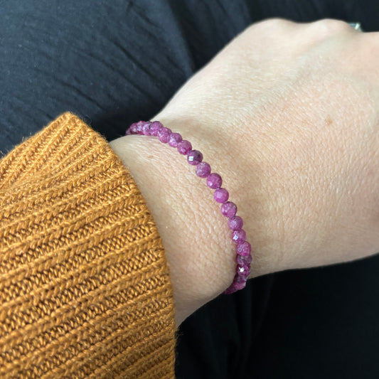 Ruby wrap bracelet on wrist, showing micro-faceted beads and flexible stainless steel wire.
