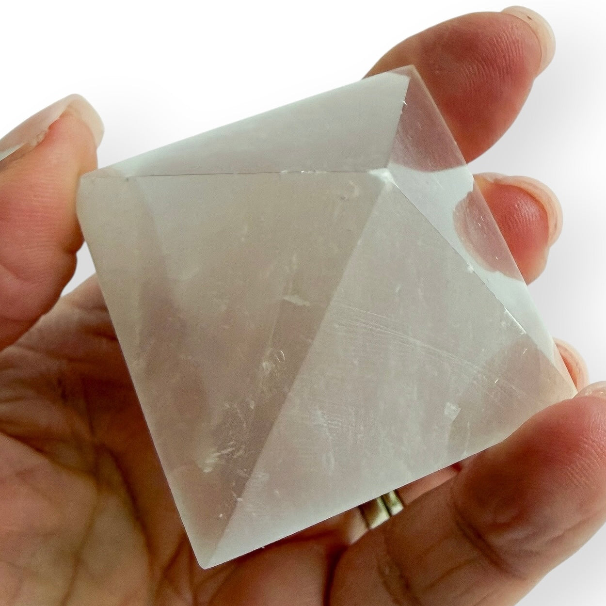 Hand holding White Satin Spar pyramid with a polished finish and natural silky chatoyancy.