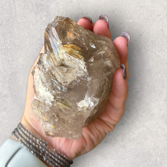 Raw Smoky Quartz with visible mica layers in hand for size reference