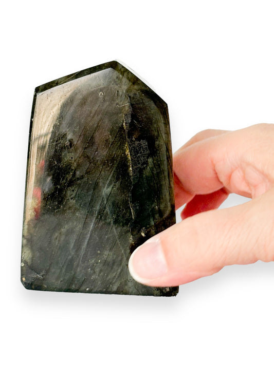 Spectrolite free form held in hand showing crystal’s size and shimmer