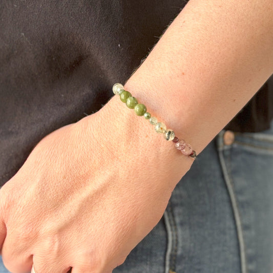 Expandable crystal bracelet worn on wrist with green and pink natural stones