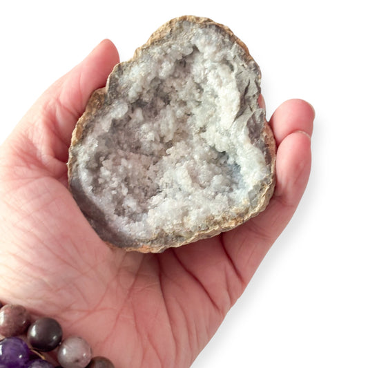 Sugar Quartz geode catching light with soft white shimmer in hand for size reference.