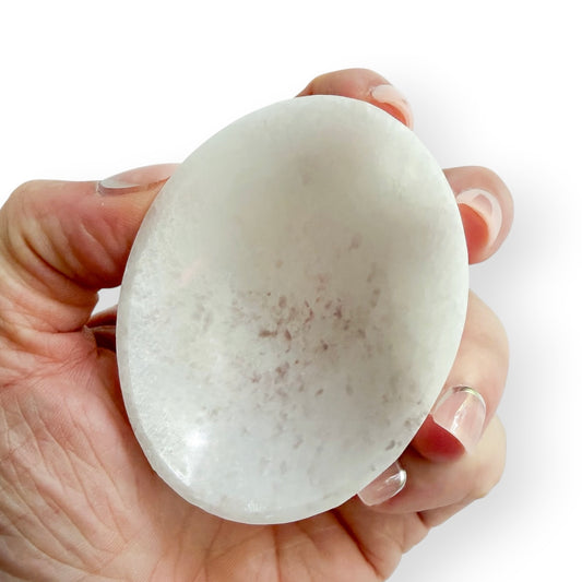 Handheld white Satin Spar oval bowl carved from natural crystal with a smooth polished finish.